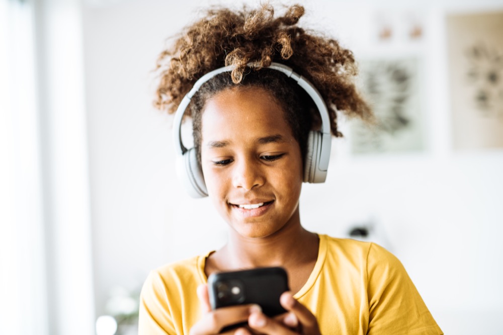 Young teenager wearing headphones playing a game on her iPad