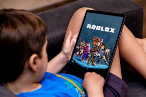a young teen playing Roblox on a tablet